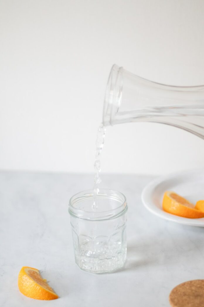 A person pouring water into a glass on a table