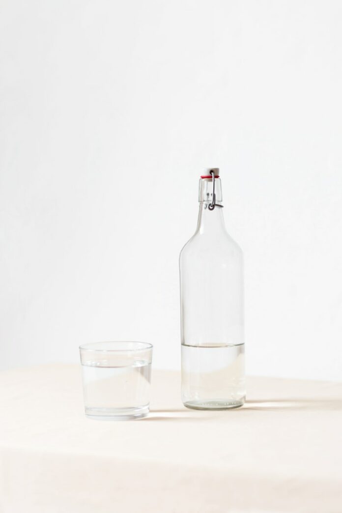 rocks glass beside half empty bottle on white surface