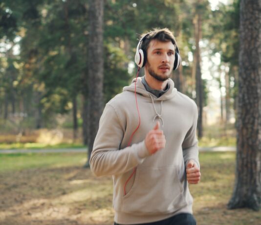 러닝 후 회복의 기술: 잘 쉬는 것도 ‘훈련’의 일부다 Man with headphones running in a forest