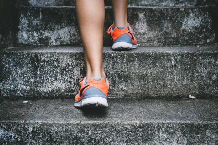 Photo by Bruno Nascimento person wearing orange and gray Nike shoes walking on gray concrete stairs